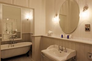 a bathroom with a sink, mirror and bathtub at Cahernane House Hotel in Killarney