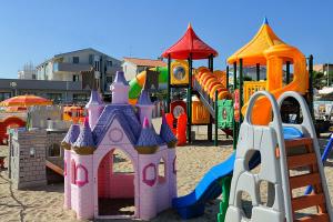 リミニにあるHotel & Residence Cavalluccio Marinoの砂の中にピンクと紫の城がある遊び場