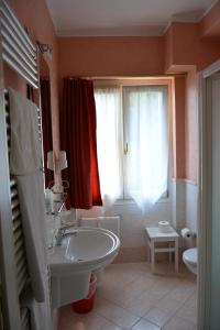 a bathroom with a tub and a sink and a window at Hotel La Terrazzina in Gargnano