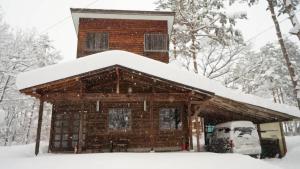 a log cabin with snow on the roof at Harmony House Hakuba in Hakuba