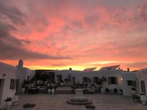 a sunset over the courtyard of a white building at Eleni's Village Suites in Klouvas