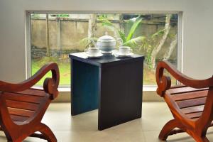 una mesa negra con 2 sillas junto a una ventana en Volunteer Ceylon en Ratnapura