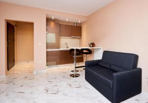 ein Wohnzimmer mit einem schwarzen Sofa und einer Küche in der Unterkunft Apartments Magic in Pomorie