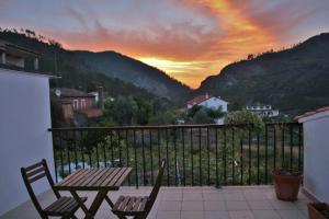 a table and chairs on a balcony with a sunset at A Casa da Lena in Foz do Cobrão