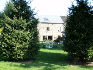 dwa drzewa przed domem ze stołem i krzesłami w obiekcie B&B La Niouche w La-Roche-en-Ardenne