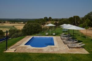 a swimming pool with lounge chairs and umbrellas at Casa Rural Finca Buenavista in Valdeganga de Cuenca