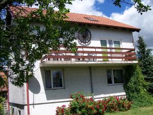 a white house with a clock on the side of it at Agrohotelik-gospodarstwo agroturystyczne in Mrągowo