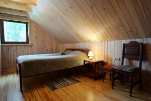 a bedroom with a bed and a window and a chair at Sodyba Latkrantė, Druskininkai in Latežeris