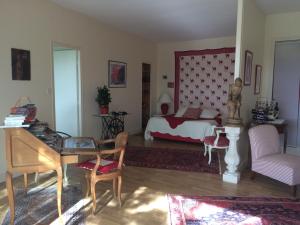 Schlafzimmer mit einem Bett, einem Schreibtisch und einem Tisch in der Unterkunft Les 4 Eléments St Emilion in Branne