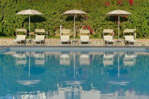 un grupo de sillas y sombrillas junto a una piscina en Hotel Mareluna, en Castellabate