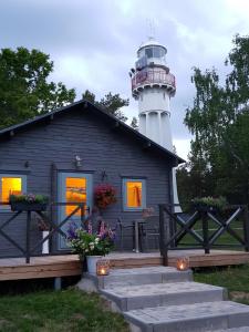 a small house with a lighthouse in the background at Camping Noras in Mērsrags