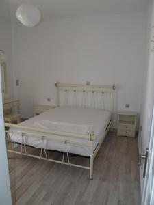 a bedroom with a white bed and a wooden floor at Vasiliki's House in Naxos Chora