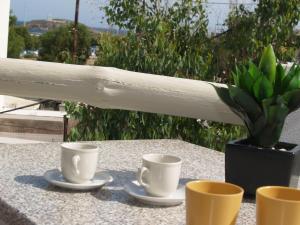 three coffee cups and a potted plant on a table at Vasiliki's House in Naxos Chora