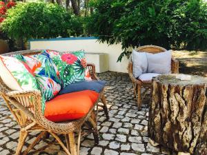 a patio with wicker chairs and a table with pillows at Casa do Páteo in Aldeia do Meco