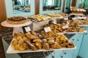 una panadería con diferentes tipos de pasteles y pasteles en Hotel Miramare en Lignano Sabbiadoro