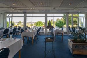 ein Esszimmer mit Tischen, Stühlen und Fenstern in der Unterkunft Hotel Juelsminde Strand in Juelsminde