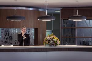 a woman standing in front of a counter with a vase of flowers at Strand Spa & Conference Hotel in Pärnu