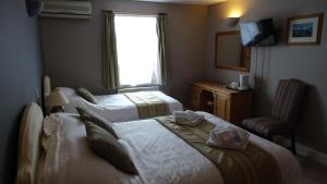 a hotel room with three beds and a television at The Furze Bush Inn in Newbury
