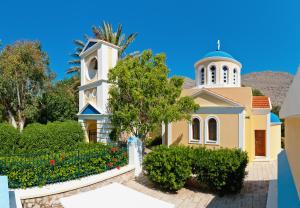 a church with a tower and a clock at Pedi Beach Hotel in Symi