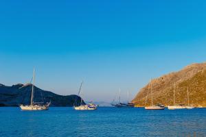 a group of boats sitting in the water next to a hill at Pedi Beach Hotel in Symi