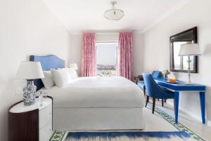 a bedroom with a white bed and a blue desk at The Phoenicia Malta in Valletta