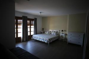 ein Schlafzimmer mit einem Bett, einer Kommode und einem Fenster in der Unterkunft Casa Perarruga in Pozán de Vero