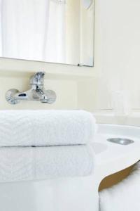 a bathroom with a sink and a mirror and towels at Premiere Classe Brive La Gaillarde Ouest in Brive-la-Gaillarde