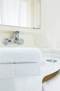 La salle de bains est pourvue d'un lavabo, d'un miroir et de serviettes. dans l'établissement Premiere Classe Brive La Gaillarde Ouest, à Brive-la-Gaillarde
