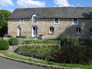 een stenen huis met een vijver ervoor bij Les chambres de La Métairie du Dick in Pleurtuit