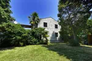 una casa blanca con una palmera en el patio en Villa Funtana, en Funtana