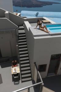 a man and a woman sitting on the roof of a house at Aria Suites & Villas in Fira