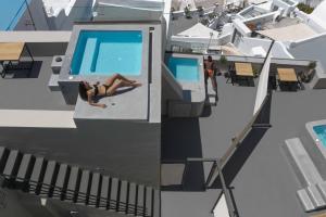 a woman laying on a pool on a cruise ship at Aria Suites & Villas in Fira