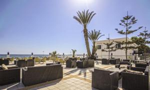 um pátio na praia com cadeiras e uma palmeira em Royal Mirage Agadir em Agadir