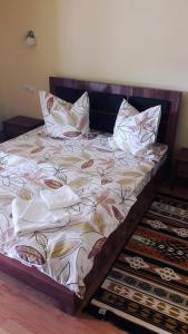 a bed with pillows on it in a room at Pensiune Restaurant la Pogace in Săpînţa