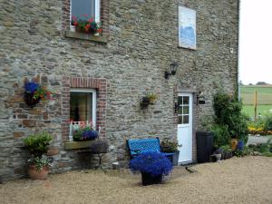 kamienny budynek z kwiatami i niebieską ławką przed nim w obiekcie B&B La Niouche w La-Roche-en-Ardenne