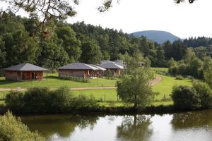 eine Gruppe von Cottages neben einem Wasserkörper in der Unterkunft Vacancéole - Le Domaine des Monédières in Meyrignac-lʼÉglise