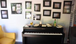 a piano in a room with a wall with pictures at Hotel Grand Canyon du Verdon in Aiguines