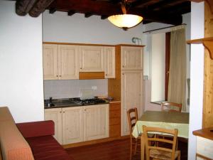 a kitchen with white cabinets and a table and a table and chairs at House Roberto by Holiday World in Castel del Piano