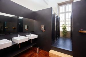 une salle de bain avec deux lavabos et un grand miroir dans l'établissement The Passenger Hostel, à Porto
