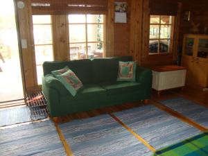 a green couch sitting in a room with windows at Mökki Eteläranta in Mikkeli