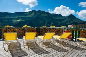 eine Gruppe von Stühlen auf einer Terrasse mit einem Berg in der Unterkunft Hotel Hertehof in Damüls
