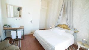 a white bedroom with a bed and a chair at Locanda Garzelli in Quercianella