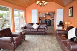 a living room with leather couches and a kitchen at Taigh na Mara in Kames