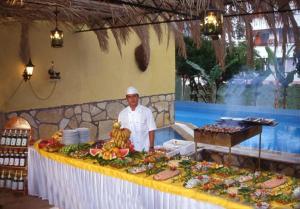 a chef standing in front of a table of food at Kleopatra Carina Hotel in Alanya