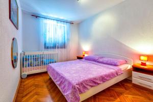 ein Schlafzimmer mit einem Bett mit violetter Bettwäsche und einem Kinderbett in der Unterkunft Hana in Mali Lošinj