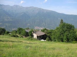 an old house in a field with mountains in the background at B&B Baita Evelina in San Giorio