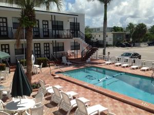 una piscina con sillas blancas y un hotel en Napoli Belmar Resort, en Fort Lauderdale