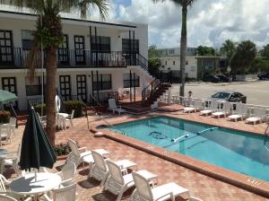 a swimming pool with white chairs and a hotel at Napoli Belmar Resort in Fort Lauderdale