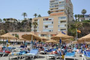 a beach with people sitting in chairs and umbrellas at Apartamento Roca Bajondillo in Torremolinos