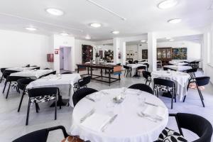 Hotel La Bussola في مارينا دي ماسا: غرفة طعام مع طاولات بيضاء وكراسي سوداء